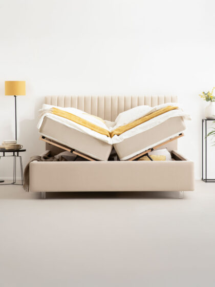 a creme-beige bed in a bedroom with bed frame for storage